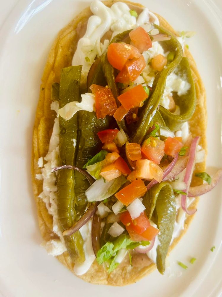 A huarache topped with nopales, pico de gallo, crema and queso fresco